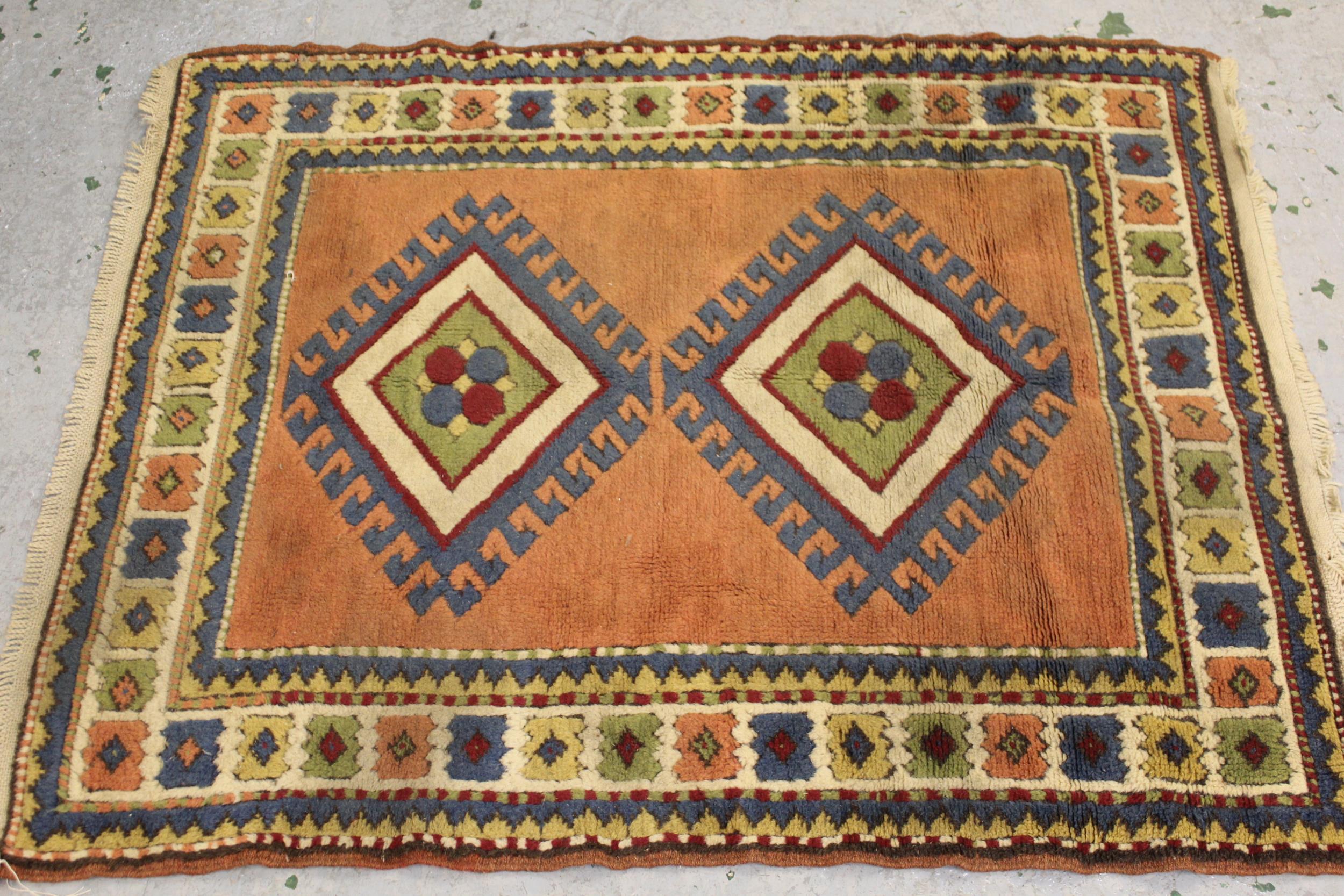 Small Turkish rug with a twin hooked medallion design on a rose ground with borders, 132cms x 108cms