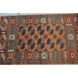 Pakistan rug of Turkoman design with two rows of gols on a pink ground with borders, 147cms x 90cms