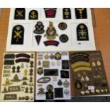Four cards mounted with various British Army and other cloth and metal badges