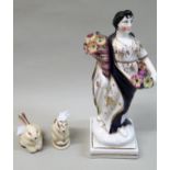 Porcelain figure of a lady in blue robe, holding a cornucopia, 24cms high, together with a Clarice