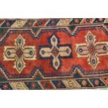 Small Turkish rug with triple medallion design on a red ground with borders, 66cms x 136cms,