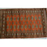 Pakistan rug of Turkoman design with two rows of gols on a rust ground with borders, 150cms x 90cms