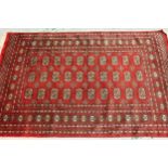 Pakistan Bokhara rug with three rows of gols on a red ground, 189cms x 125cms, together with a