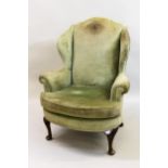 20th Century green upholstered wingback armchair with loose cushion, raised on carved cabriole and
