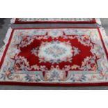 Pair of Chinese rugs with medallion and floral design on a red ground, 185cms x 125cms