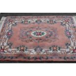 Chinese rug with medallion and floral design on a pink ground, 183cms x 122cms together with a