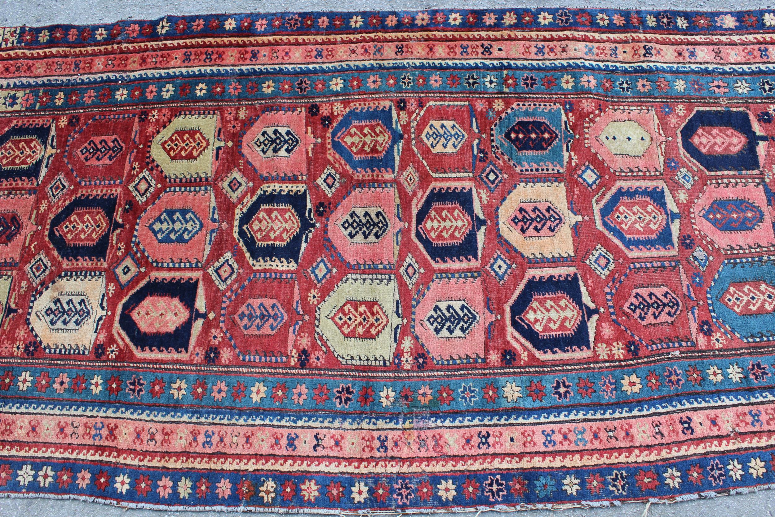 Kazak runner with an all-over stylised design on a brick red ground with borders, 250cms x 108cms