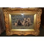 An ornate gilt framed colour print of fisherfolk on a beach, together with another of a cow and