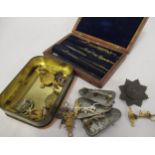 Tin containing a small quantity of various military badges and a small mahogany cased drawing set (