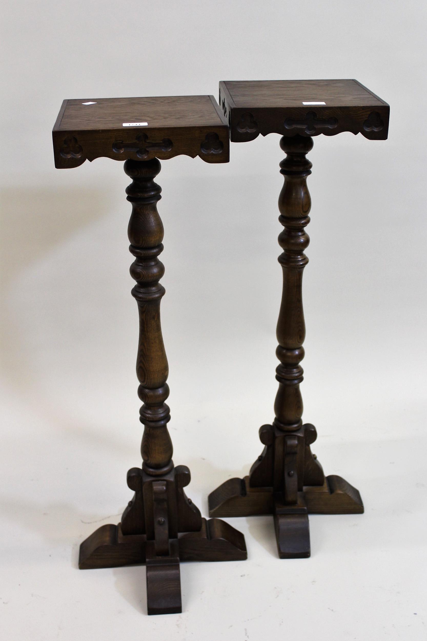 Pair of reproduction oak torcheres, the Gothic style square tops above baluster columns and