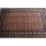 Pakistan rug of Turkoman design with three rows of gols on a rust ground, 185cms x 125cms