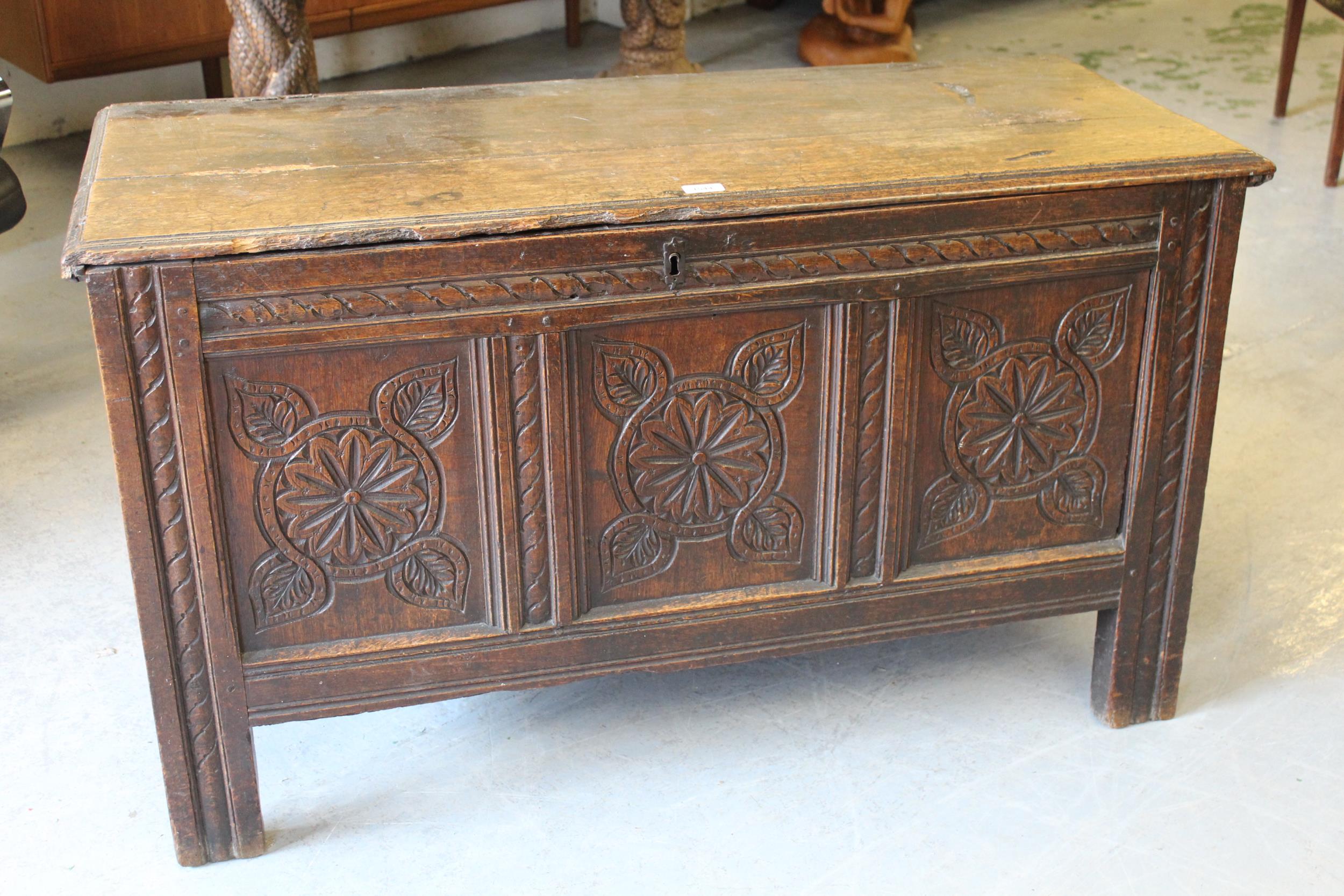 17th Century oak coffer, the moulded hinged top above carved three panel front on stile supports,