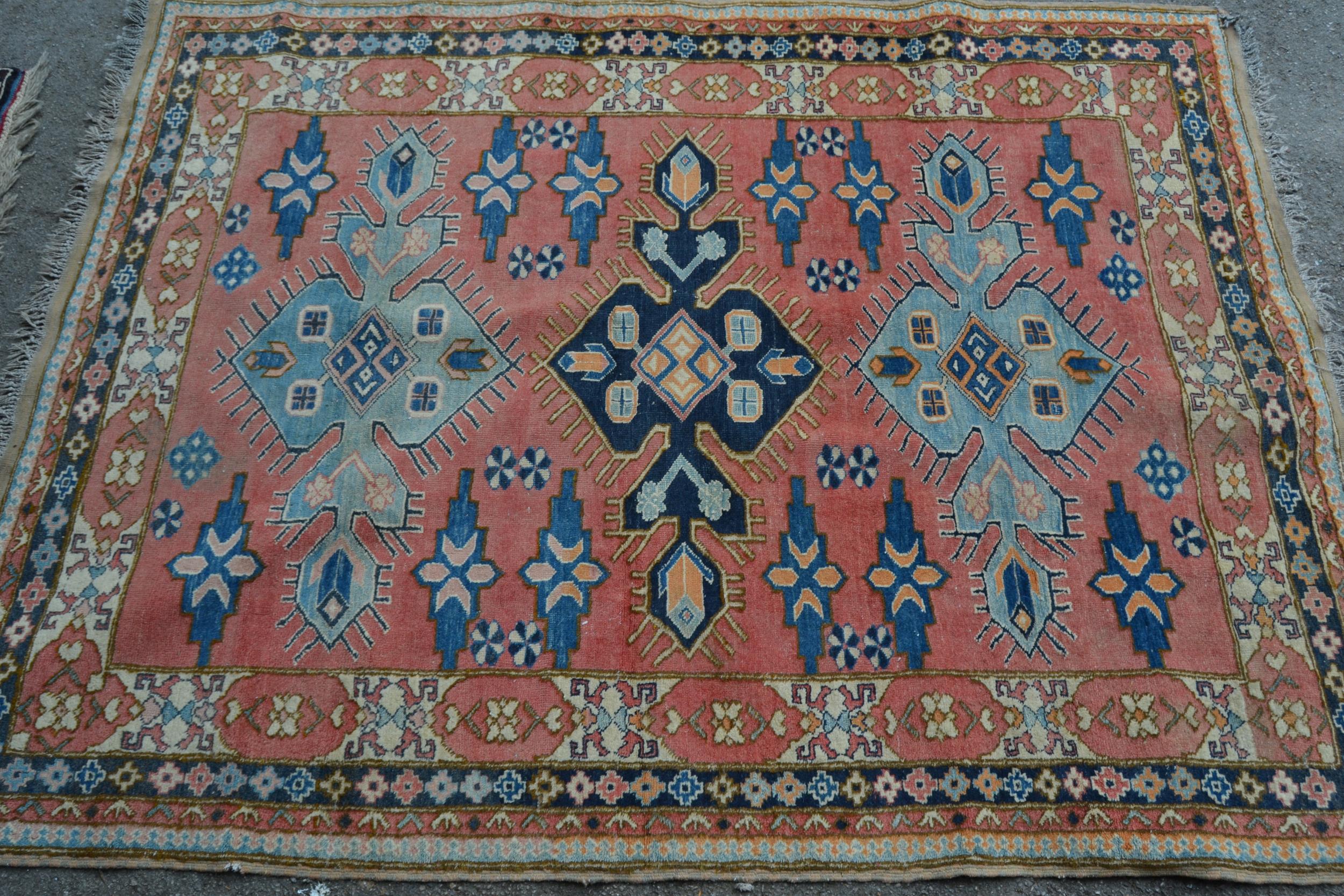 Turkish rug of Caucasian design with triple medallion on a rose ground with borders, 184cms x 145cms