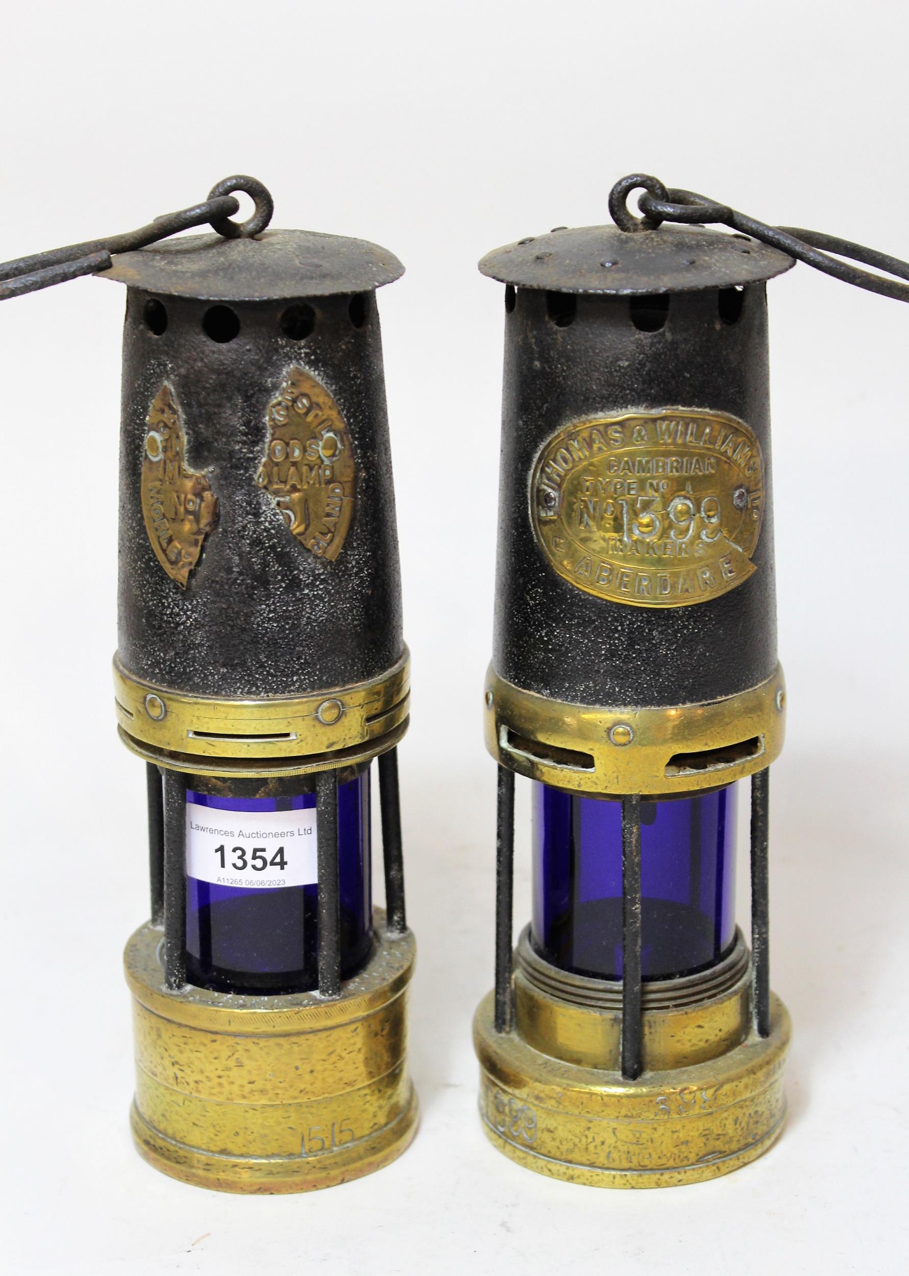 Two early metal and brass miners lamps, both with blue glass lenses, one marked E. Thomas & Williams