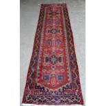 Hamadan runner with a repeating medallion and all-over stylised floral design on a red ground with