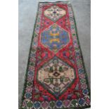 Kurdish runner with a triple medallion design on a rose ground with borders, 266cms x 99cms