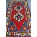 Anatolian rug with a twin medallion design on a red ground with borders, 221cms x 122cms
