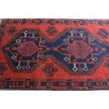 Belouch rug with a triple medallion design in shades of red, blue, brown and orange, 190cms x 115cms