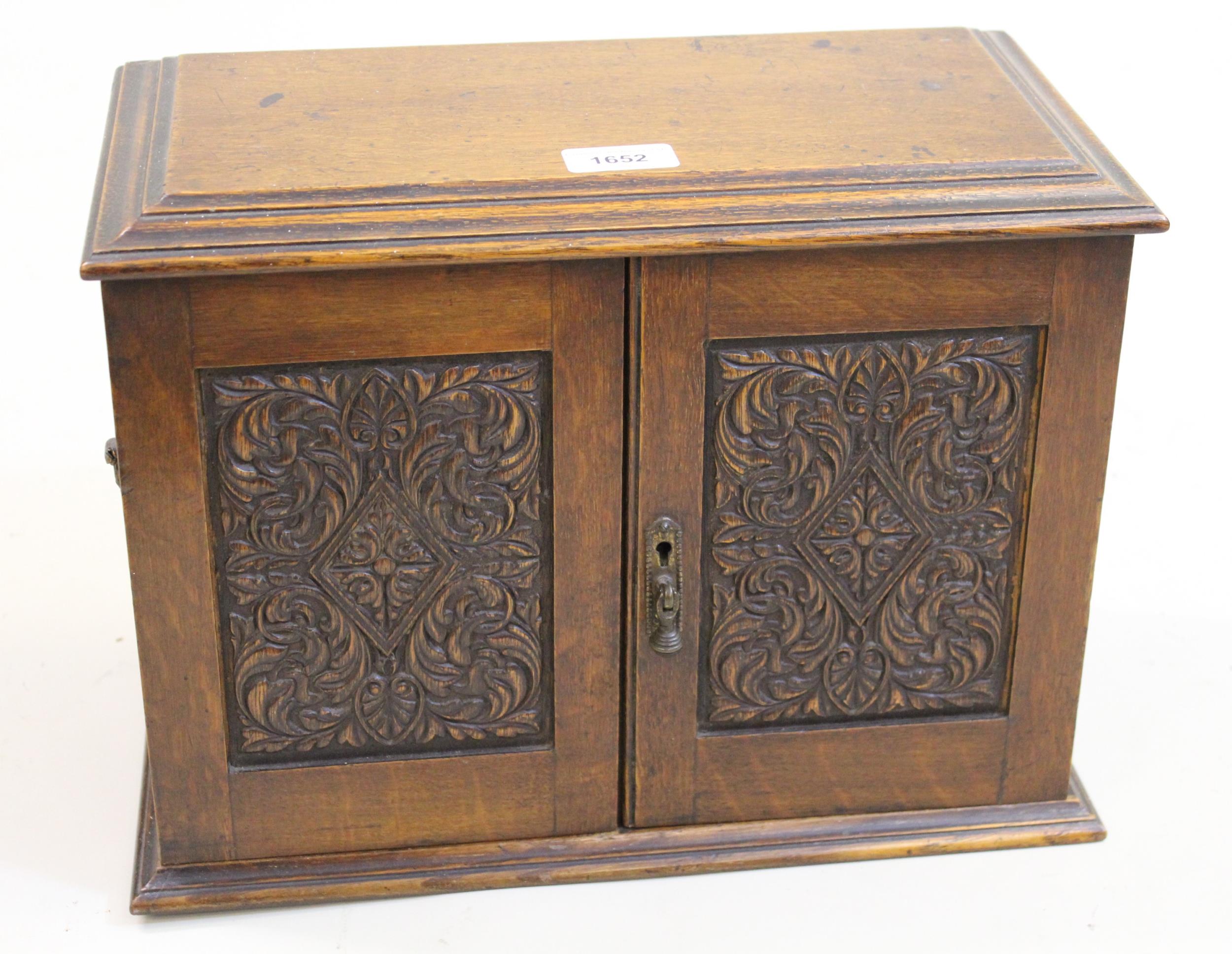 Late 19th / early 20th Century oak smoker's cabinet having two carved panel doors enclosing a fitted