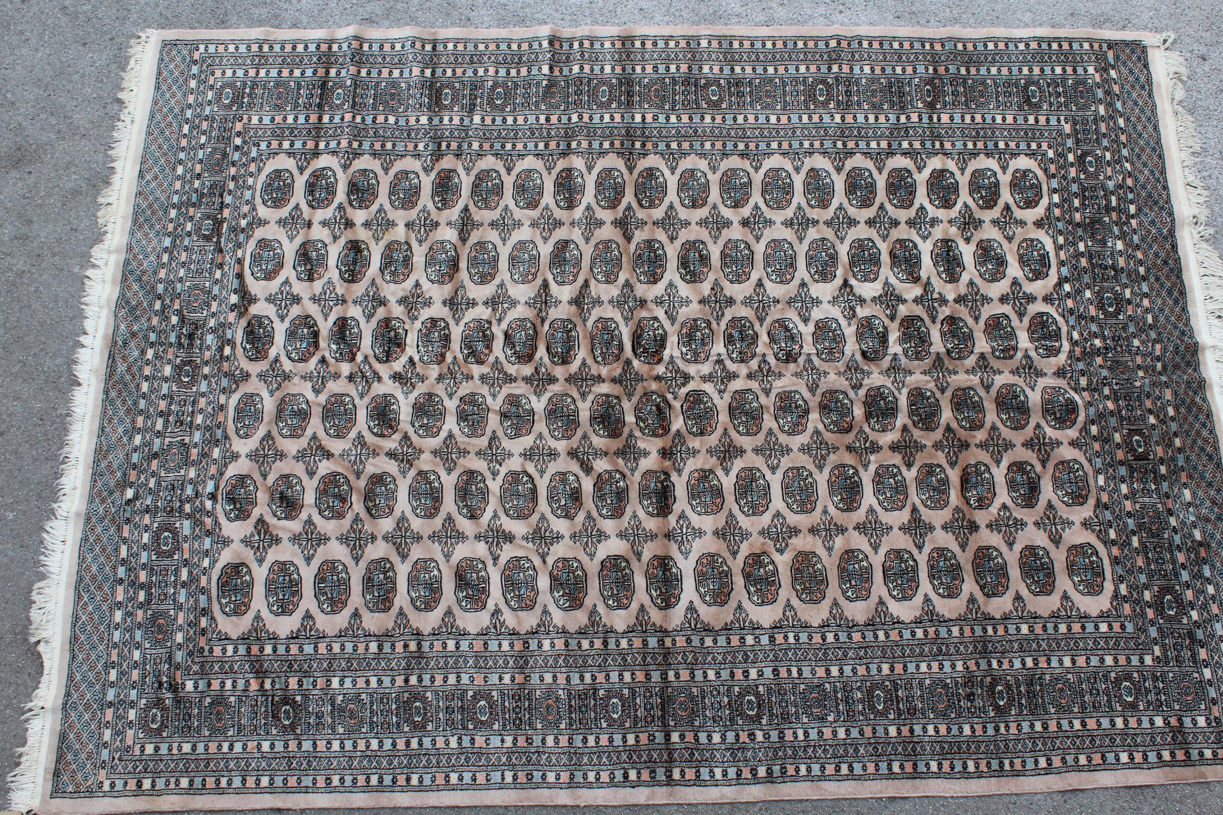 Pakistan Bokhara carpet with six rows of gols on a beige ground with borders, 10ft x 7ft 4ins