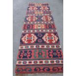 Kelim runner with all-over hooked medallion design in shades of red, blue, cream and yellow,