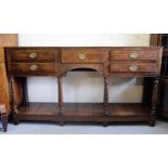 George III oak dresser base with an arrangement of five drawers with oval brass handles, surrounding