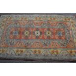 Modern Turkish rug with a line of central medallions on rose pink ground with twin borders, 201cms x