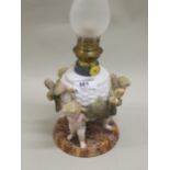 Late 19th Century Continental porcelain oil lamp in the form of putti supporting a basket, 37cm high