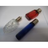 Three early 20th Century glass perfume bottles in clear, Bristol blue and cranberry colours