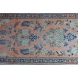 Small Sarouk vase rug with stylised floral designs on a pink ground with borders, 136 x 66cm