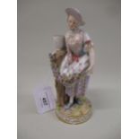 Meissen figure of a lady standing beside a tree stump with a garland of flowers, 18cm high (damages)