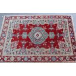 Indian carpet with a lobed medallion and stylised floral sprig design on a red ground with
