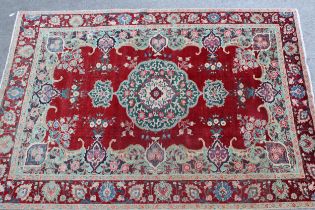 Indian carpet with a lobed medallion and stylised floral sprig design on a red ground with