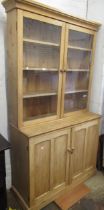 19th Century stripped pine bookcase, the top having two glazed doors enclosing shelves above two
