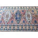 Kazak rug with a triple medallion design on a rose ground with rosette border, 218 x 146cm Some