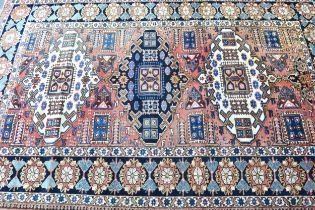 Kazak rug with a triple medallion design on a rose ground with rosette border, 218 x 146cm Some