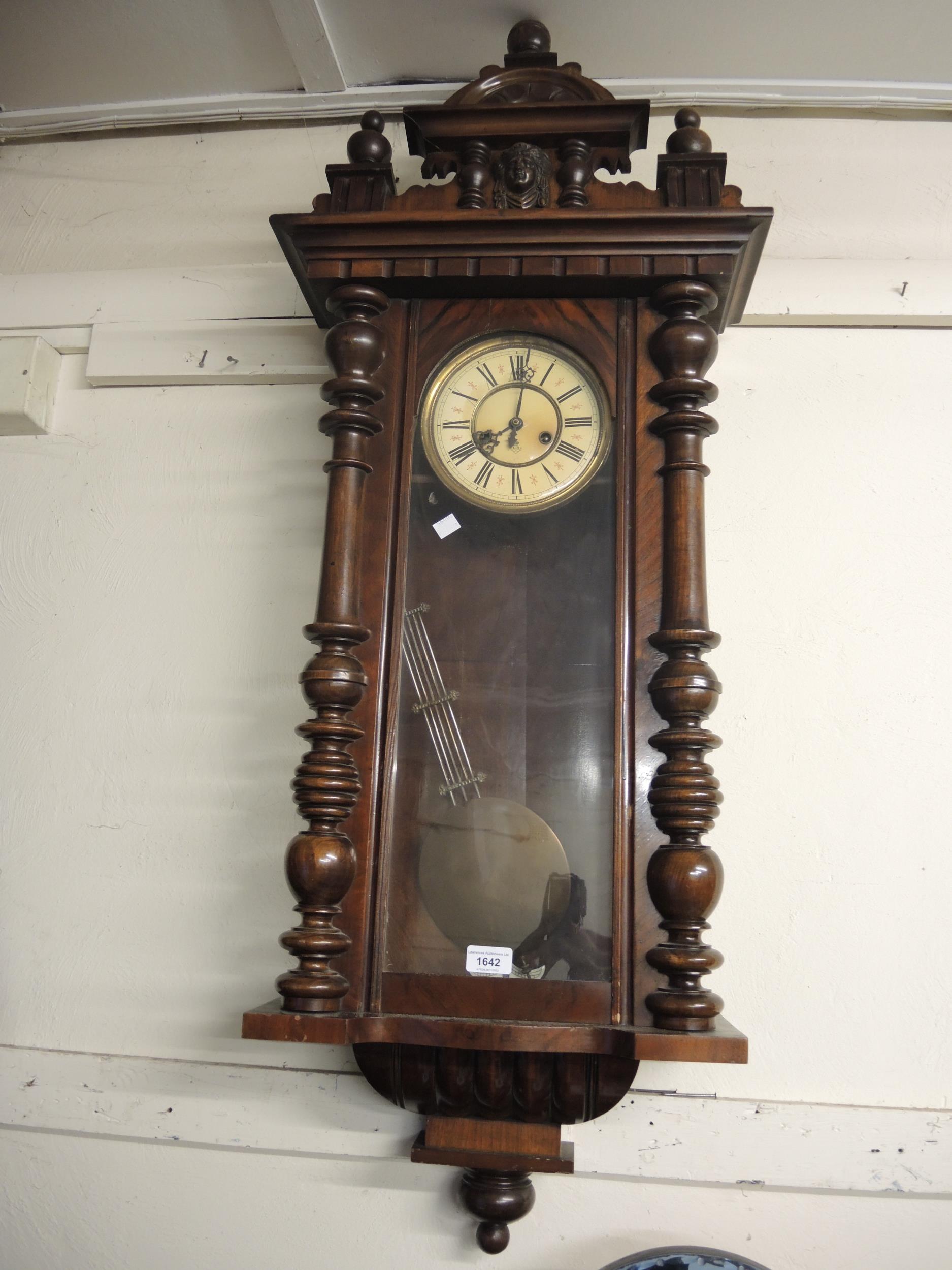 Late 19th Century walnut Vienna type wall clock with a mask head surmount above a painted dial