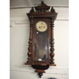 Late 19th Century walnut Vienna type wall clock with a mask head surmount above a painted dial