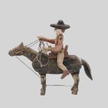 A FOLK ART PAINTED AND ARTICULATED COWBOY ON HORSEBACK.
