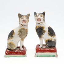 A PAIR OF 19TH CENTURY STAFFORDSHIRE POTTERY CATS.