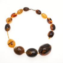 A STRING OF LARGE GRADUATED MULTI-COLOURED AMBER BEADS.