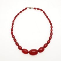 A SINGLE ROW GRADUATED RED AMBER BEAD NECKLACE.