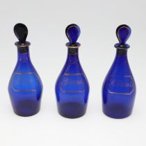 A SET OF THREE REGENCY BLUE GLASS DECANTERS.