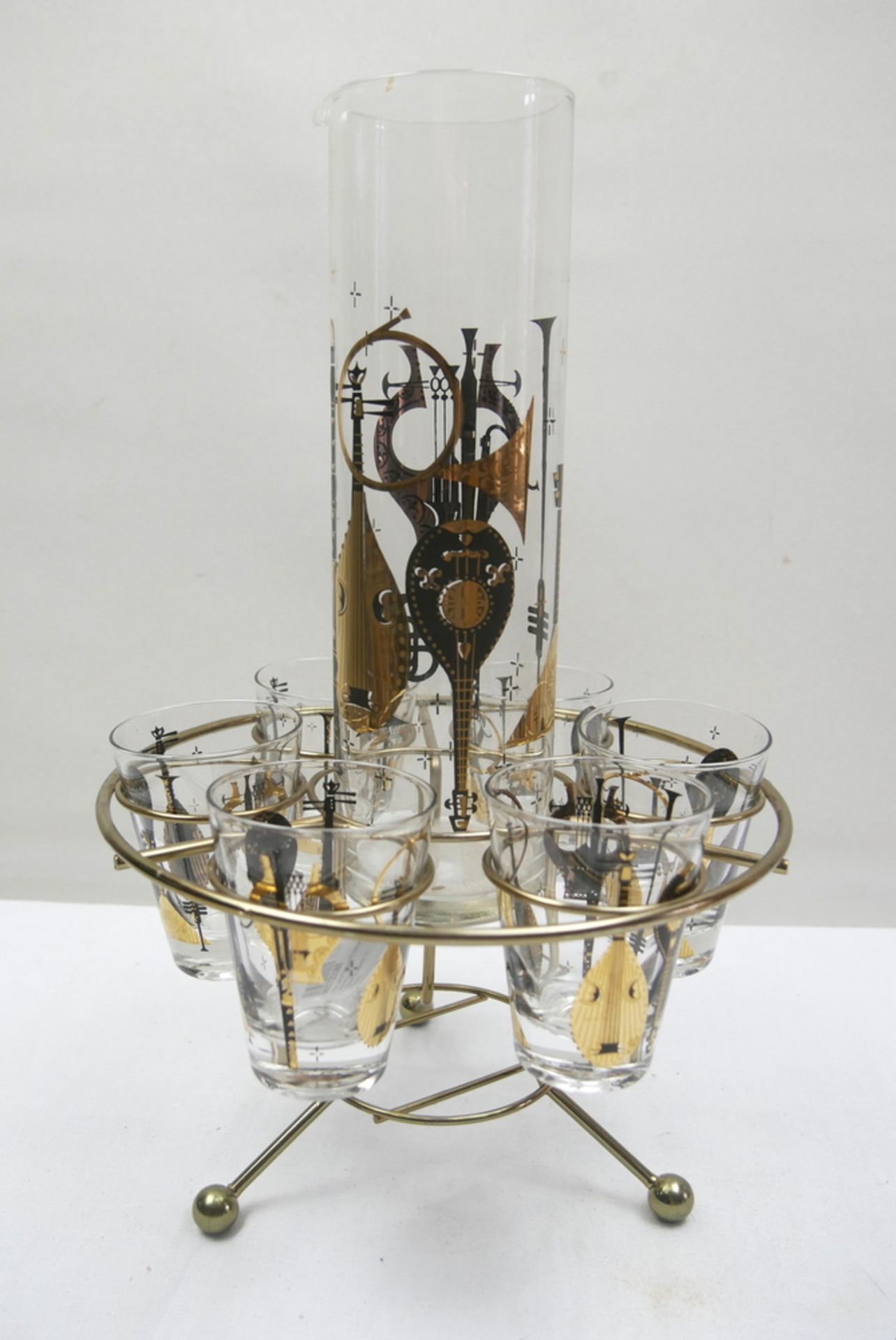 60er Jahre Krug und 6 Gläser mit Aufdruck "Musikinstrumente" im Gestell.