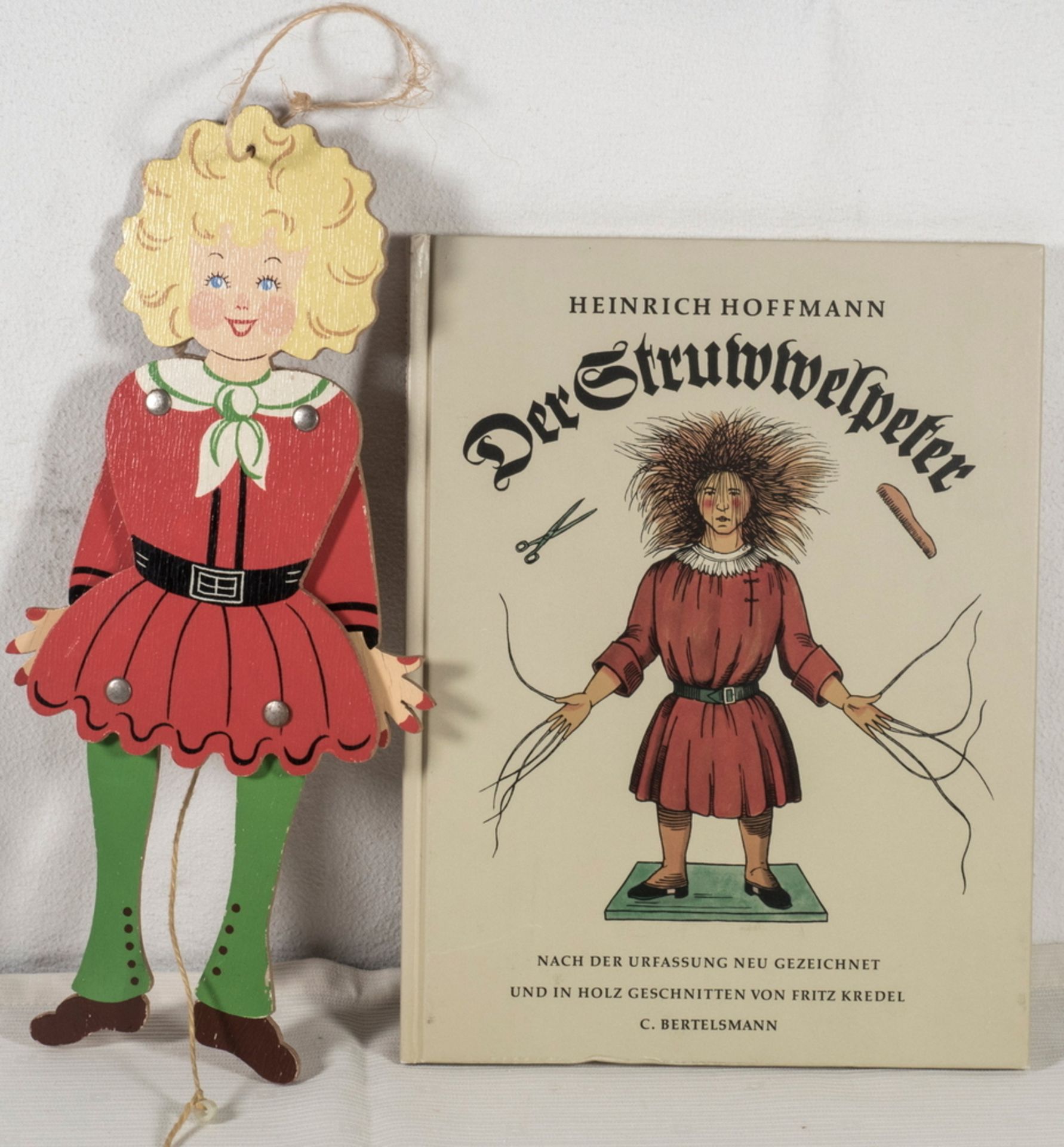 Struwwelpeter - Buch, dazu Struwwelpeter als Hampelmann. Holz. Höhe: ca. 29 cm.