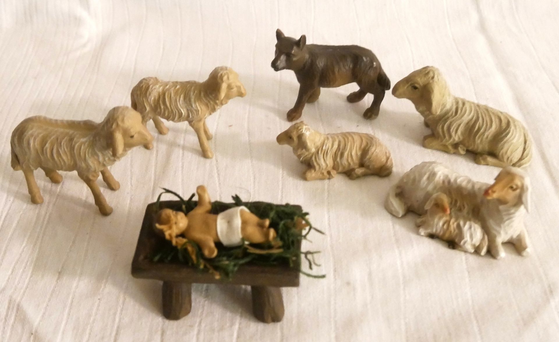 Lot Krippenfiguren, bestehend aus 5 Schafen, 1 Hund / Wolf sowie Jesukind in der Krippe.