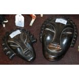 TWO EARLY 20TH CENTURY ART DECO CARVED AND STAINED STONE AFRICAN STYLE WALL MASKS DEPICTING STYLISED