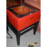 AN ORIENTAL RED AND BLACK LACQUER HOT PLATE, THE SQUARE SHAPED TOP WITH GLASS INSERT ABOVE A