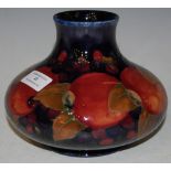 A MOORCROFT BLUE GROUND POTTERY VASE DECORATED WITH POMEGRANATES, IMPRESSED MARKS, 12CM HIGH