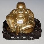 A CHINESE GILT METAL FIGURE OF BUDDHA ON CARVED AND PIERCED WOOD STAND, OVERALL 21CM HIGH